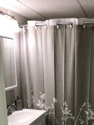 Bathroom with toilet, sink, mirrored cupboard, and shower.